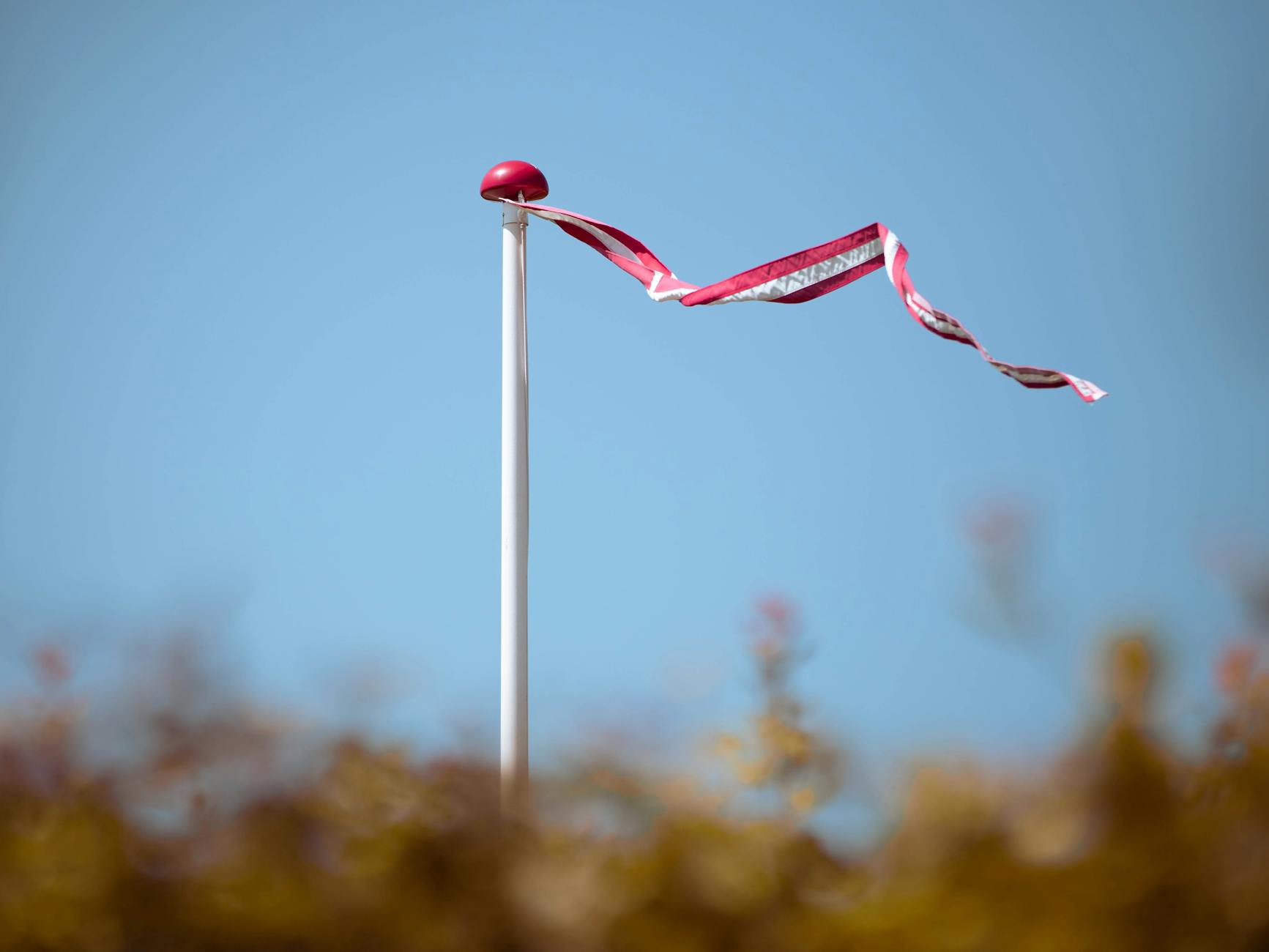 red and white flag on a pole against blue sky